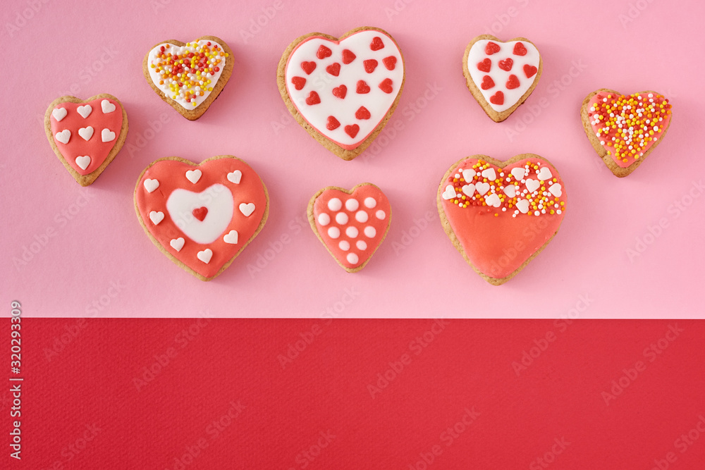 Decorated heart shape cookies on a colored red and pink background, top view