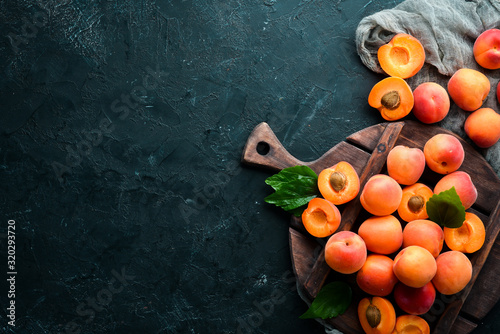 Fresh apricots with green leaves on a black background. Rustic style. Top view. Free space for your text. photo