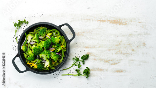 Green vegetables stewed in a frying pan. Broccoli, beans, green peas. Top view. Free space for your text.