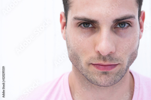 Horizontal portrait of handsome young man staring by white background