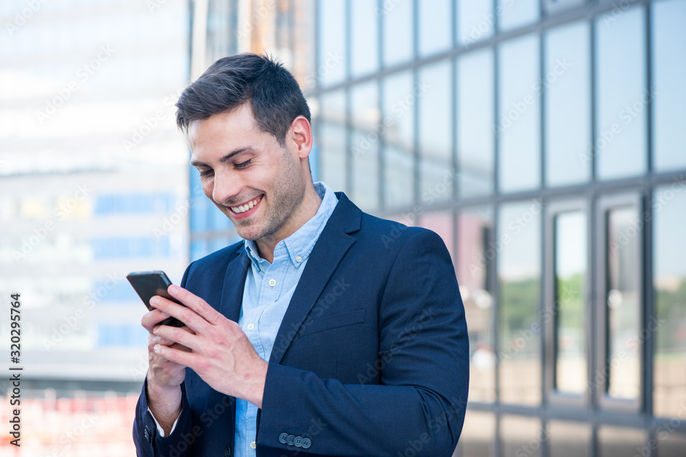 Close up smiling businessman looking at cellphone in city Close up smiling businessman looking at cellphone in city