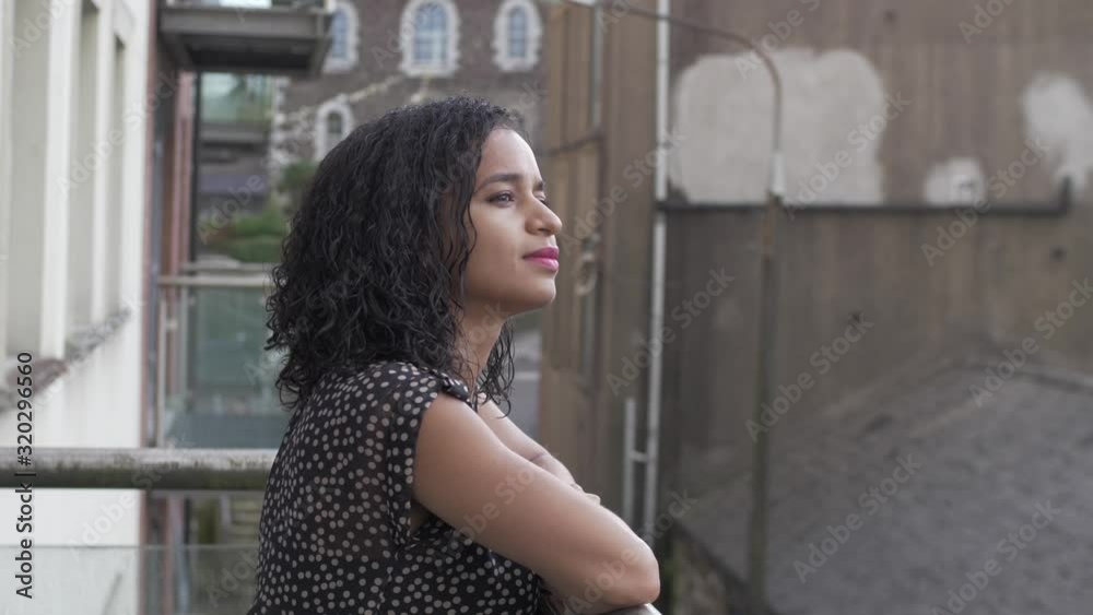 A young lady is relaxing on a balcony and observing the neighbourhood. A young lady is relaxing on a balcony and observing the neighbourhood.
