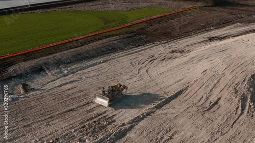 Rotating shot of a multi terrain tractor loader compacting foundation dirt. photo