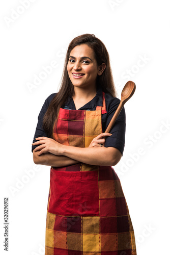 Canvas-taulu Indian / asian woman chef wearing Apron and holding wooden spatula while standin