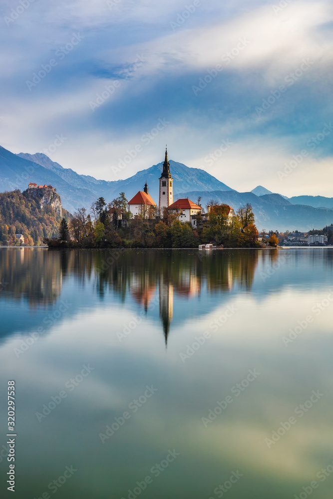Island with a church and reflection in calm water of lake Bled, famous natural attraction of Slovenia