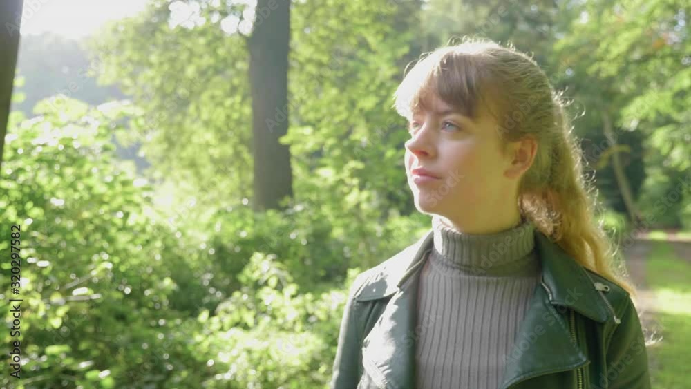 Smiling young woman walks nature path on sunny day, tracking Smiling young woman walks nature path on sunny day, tracking