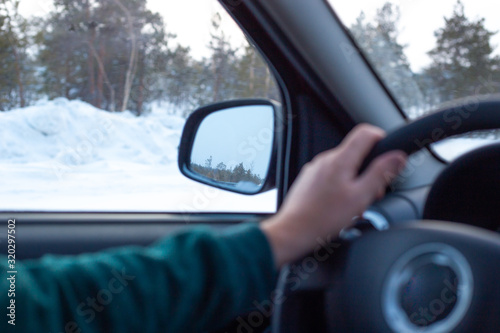 mature man drives a car on a winter road, inside view