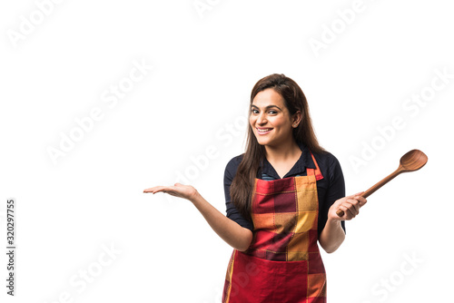 Fotografie Indian / asian woman chef wearing Apron and holding wooden spatula while standin