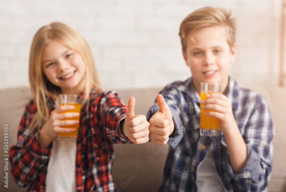 Boy And Girl Drinking Juice Gesturing Thumbs-Up Sitting On Sofa Boy And Girl Drinking Juice Gesturing Thumbs-Up Sitting On Sofa
