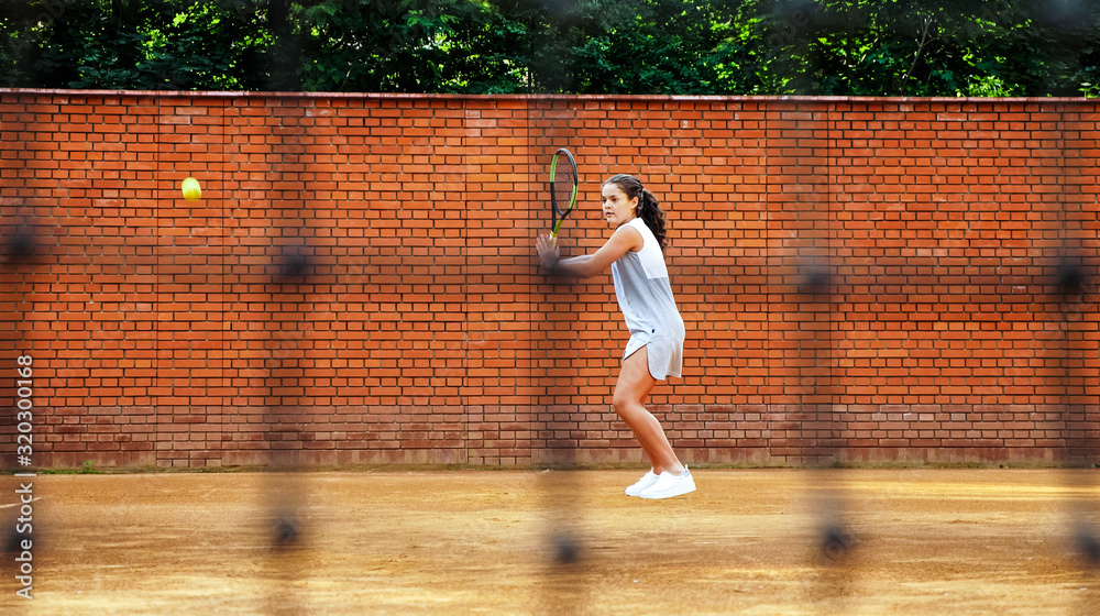 Young girl blocking the ball with the tennis racket during the training