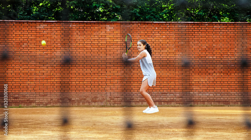 Young girl blocking the ball with the tennis racket during the training © alex_marina