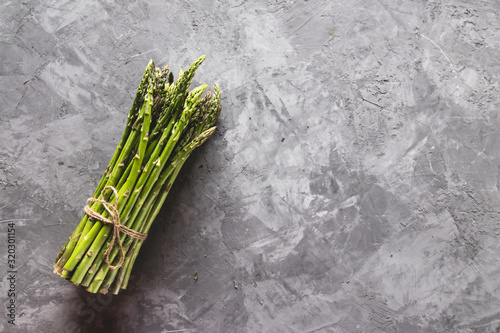 Fresh bunch of asparagus with smooth daylight on grey stone background/top view