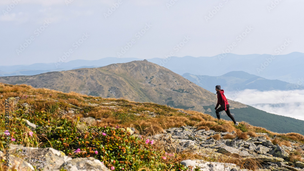 Woman is climbing a mountain ridge.