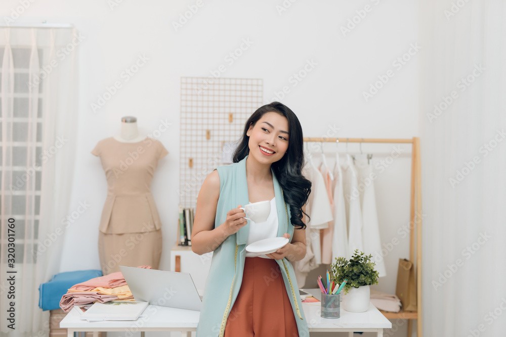 Portrait of beautiful young Asian fashion designer businesswoman at her studio while drinking coffee Portrait of beautiful young Asian fashion designer businesswoman at her studio while drinking coffee