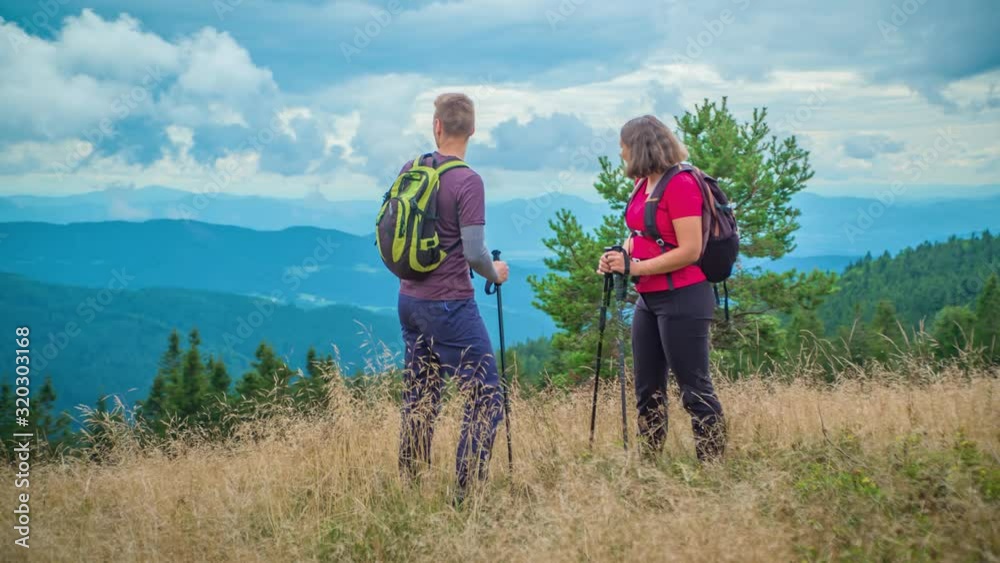 Young hiker couple admiring the beautiful view of mountains on reaching the peak of Ribnica Na Pohorju, Slovenia on cloudy day. Young hiker couple admiring the beautiful view of mountains on reaching the peak of Ribnica Na Pohorju, Slovenia on cloudy day.