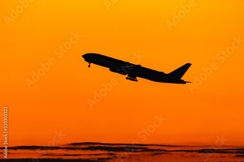 朝焼けの中離陸するジェット旅客機