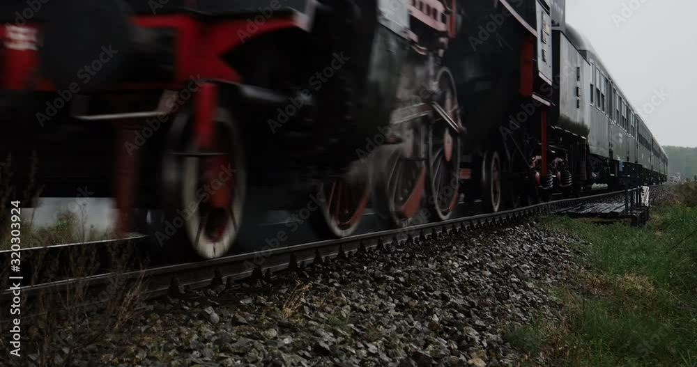 Historic steam train locomotive with railroad passenger wagons in the countryside passing by