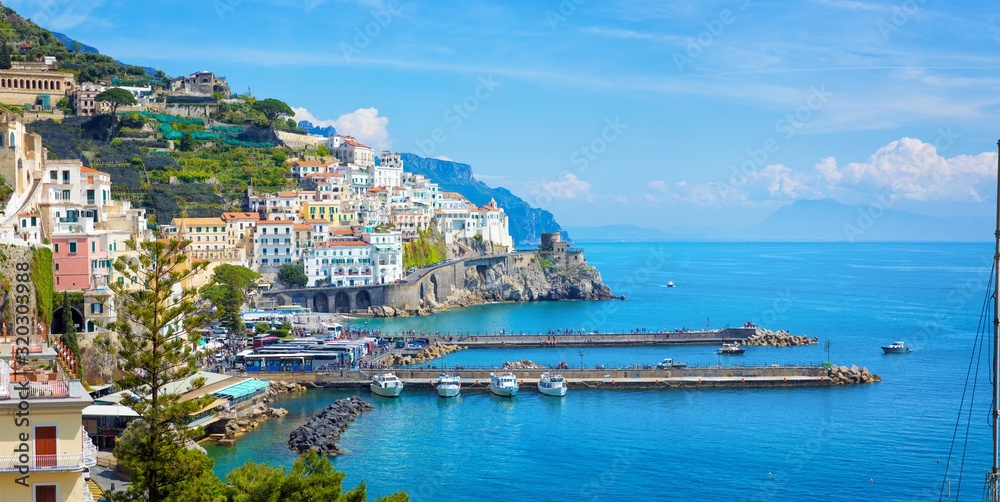 Beautiful Amalfi with hotels on hills leading down to coast, comfortable beaches and azure sea in Campania, Italy.