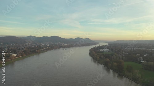 Cinematic drone /aerial shot of the river rhine with a ship and the panorama of the seven mountains / Siebengebirge Königswinter / Bonn at golden hour, 30p photo