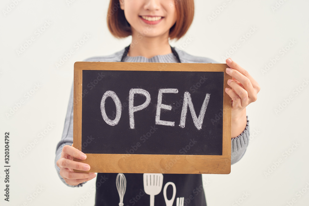 It's open here. A smiling woman is holding a sign with the inscription It's open here. A smiling woman is holding a sign with the inscription