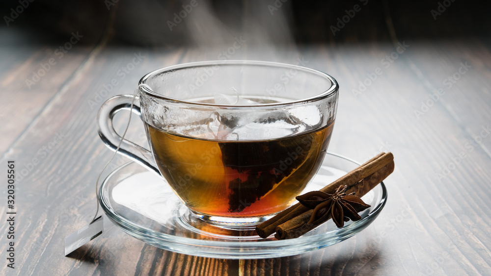 transparent cup on a saucer with a tea bag, cinnamon sticks and anise on the table transparent cup on a saucer with a tea bag, cinnamon sticks and anise on the table
