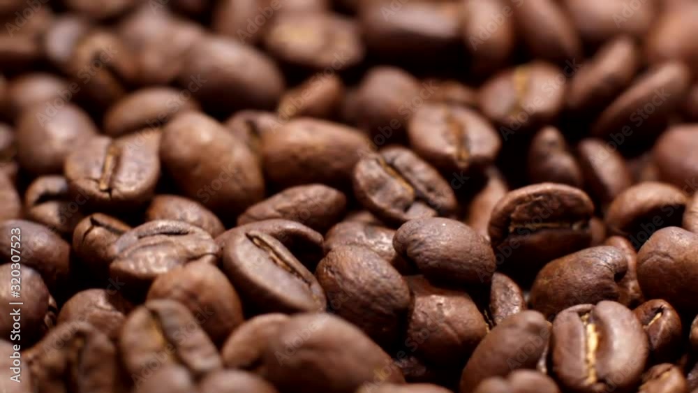 Roasted coffee beans background. Close-up of roasted coffee beans spinning slowly in a circle. Roasted coffee bean background, top view. Roasted coffee beans background. Close-up of roasted coffee beans spinning slowly in a circle. Roasted coffee bean background, top view.