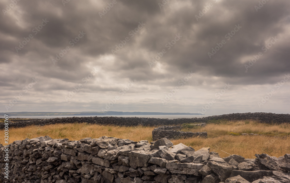 Dry limestone walls on Inisheer (Inis Oirr) the smallest of the Aran islands off the coast of Galway in the west of Ireland. The coast of county Clare can be seen in the distance.