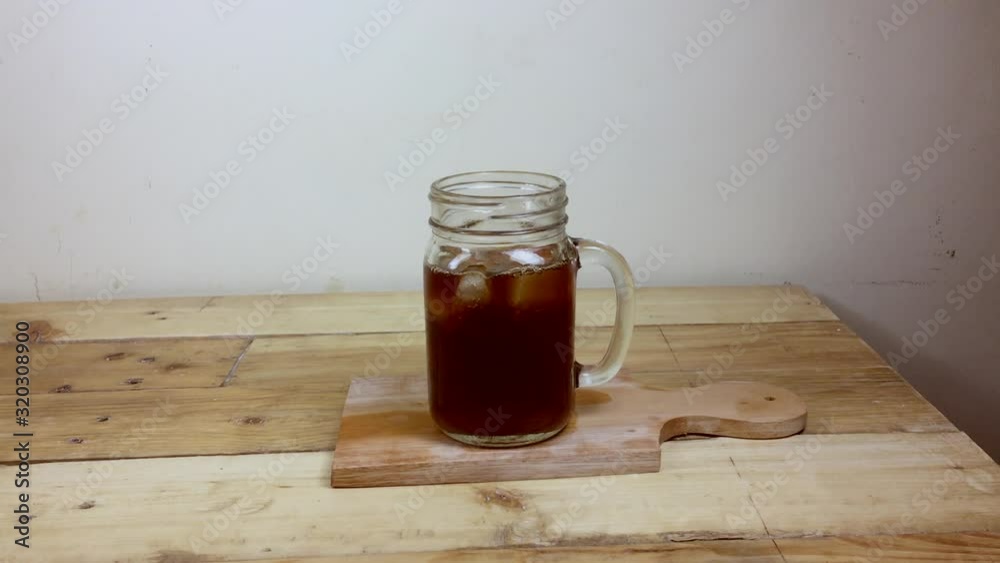 Dropping ice cubes to the glass jar with coffee. Dropping ice cubes to the glass jar with coffee.