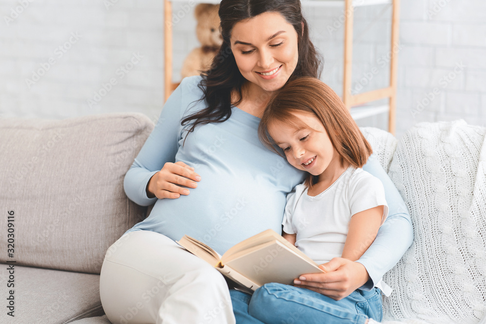 Close up of expecting woman reading to little daughter
