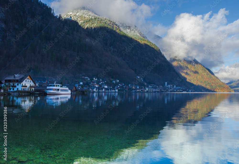 Fototapeta premium Hallstatt, a charming village on the Hallstattersee lake and a famous tourist attraction, with beautiful mountains surrounding it, in Salzkammergut region, Austria, in winter sunny day.