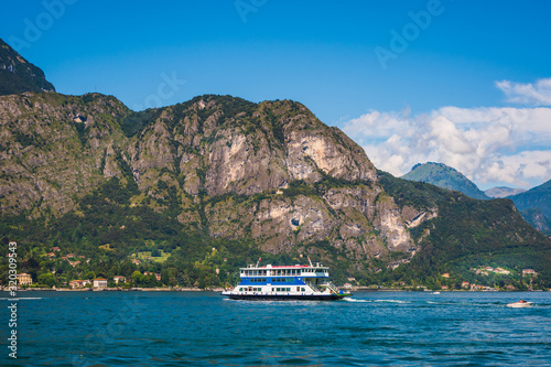 Picturesque summer landscape from Lake Como, ferry boat on the alpine lake, blue sky and high mountain in the background, Province of Como, Italy.   © Plamen Petrov