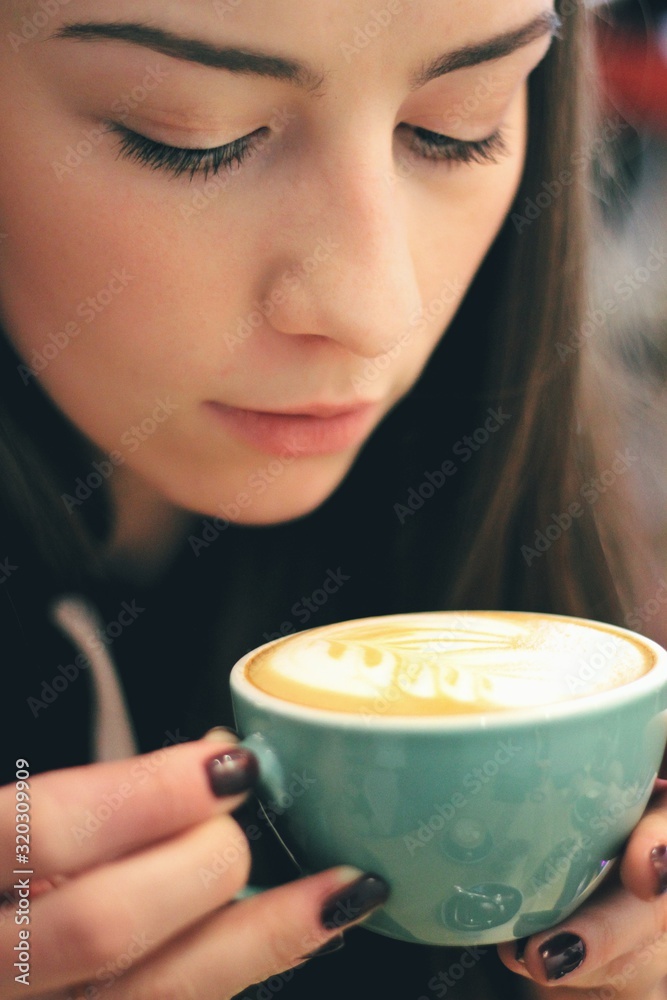 Caucasian young woman enjoying coffee drinking in cafe, close up