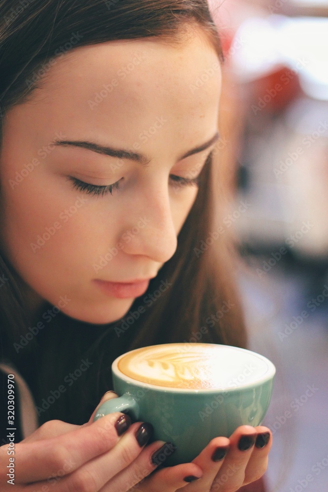 Caucasian young woman enjoying coffee drinking in cafe, close up