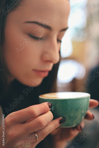 Caucasian young woman enjoying coffee drinking in cafe, close up