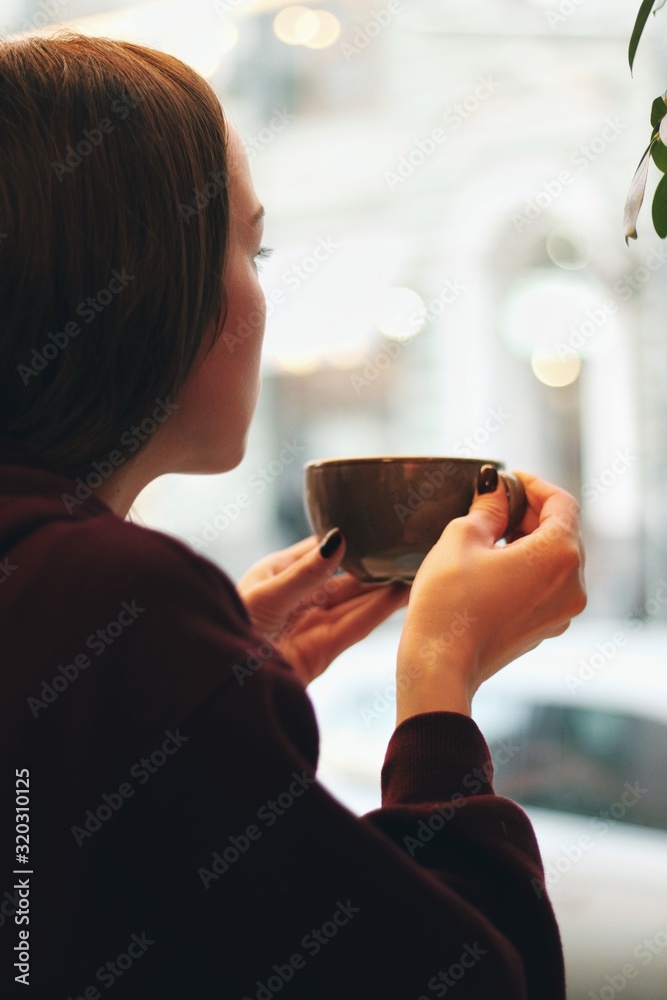 Caucasian young woman enjoying coffee drinking in cafe, close up