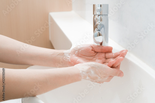 Asian woman washing hands  in a sink