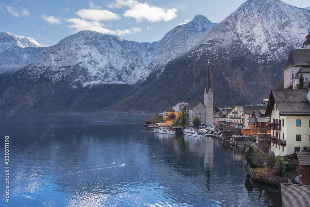 Fototapeta premium Hallstatt, a charming village on the Hallstattersee lake and a famous tourist attraction, with beautiful mountains surrounding it, in Salzkammergut region, Austria, in winter sunny day.