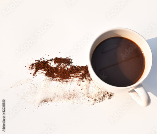 Black coffee in a white cup Coffee powder strewn loss Put on the table a white background