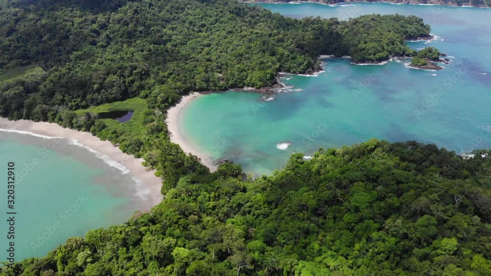Aerial shot of beach at Cathedral Point, Manuel Antonio National Park, Costa Rica. Sunny weather, clear blue green water, cloud shades over turquoise water. Flying backwards. Aerial shot of beach at Cathedral Point, Manuel Antonio National Park, Costa Rica. Sunny weather, clear blue green water, cloud shades over turquoise water. Flying backwards.