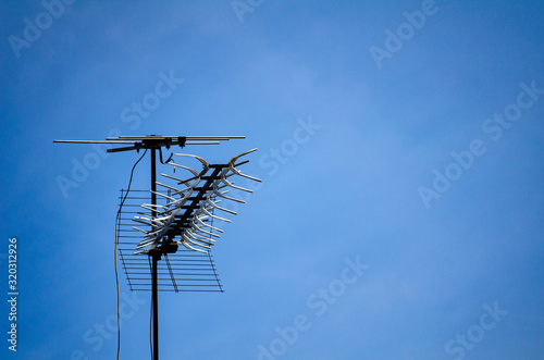 television antenna installed on roof top over blue sky background