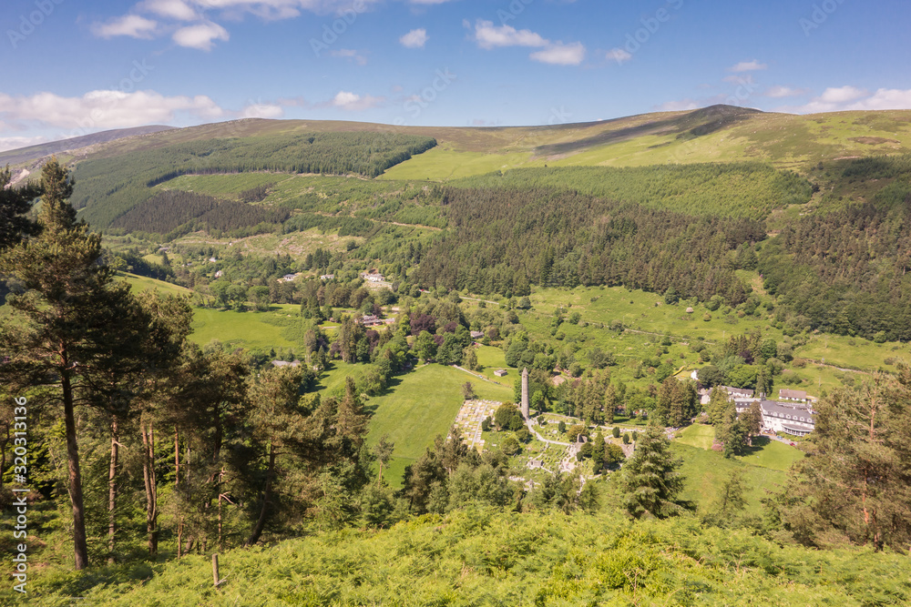 View from above of the Early Medieval monastic settlement with Round Tower, nestled in a woodland glacial valley at Glendalough National Park, County Wicklow, Ireland.