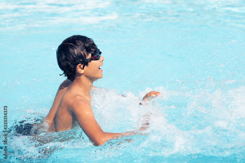 young asian boy laughing, splasking and playing in the water