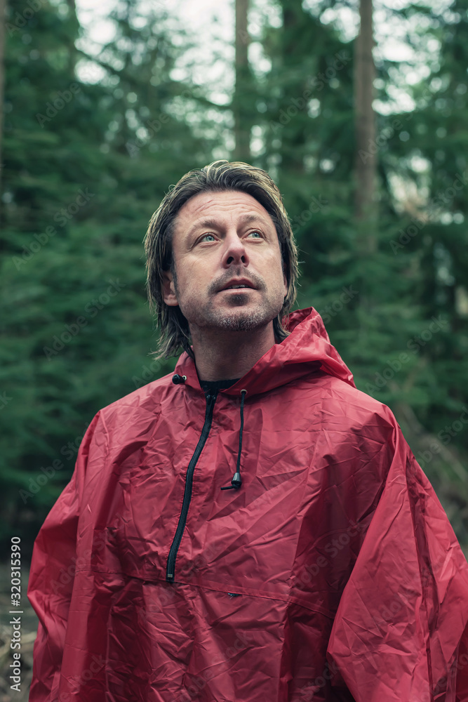 Middle aged man in red raincoat in woods. Looking up. Middle aged man in red raincoat in woods. Looking up.
