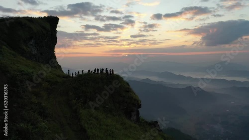 Aerial view of tourists' silhouettes and photographers taking pictures of beautiful misty scenery at the top of the mountain at sunrise. chiangrai, thailand