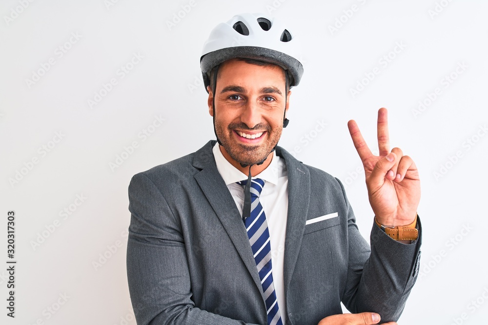 Young handsome business man wearing suit and tie and bike helmet over isolated background smiling with happy face winking at the camera doing victory sign. Number two. Young handsome business man wearing suit and tie and bike helmet over isolated background smiling with happy face winking at the camera doing victory sign. Number two.