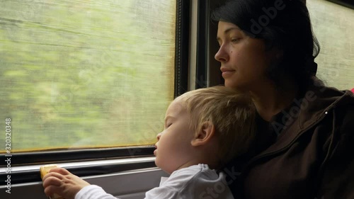 Tired Depressed Young Mother With Child. Poor Refugee Family Traveling by Old Dirty Budget SuburbanTrain. Passenger Carriage photo