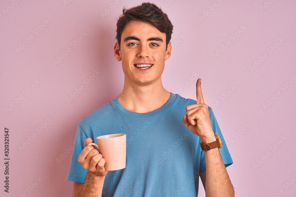 Teenager boy drinking a cup of coffee over isolated pink background surprised with an idea or question pointing finger with happy face, number one Teenager boy drinking a cup of coffee over isolated pink background surprised with an idea or question pointing finger with happy face, number one