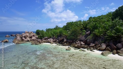 Pristine and private beach with granite rocks, palms, white sand and blue sky in Indian Ocean photo