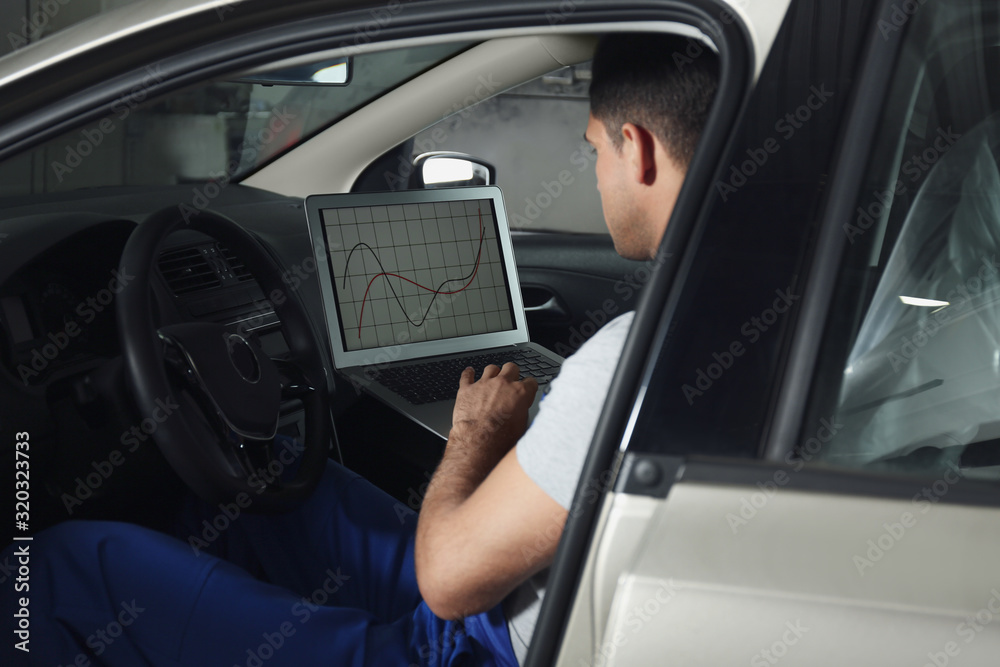 Mechanic with laptop doing car diagnostic at automobile repair shop