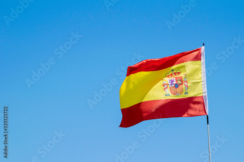 a Spanish flag blowing in the wind with blue skies in the background in Marbella  Spain